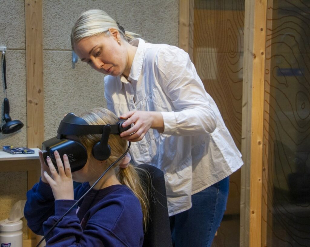 Ohjaaja laittaa oppilaalle VR-laseja päähän.