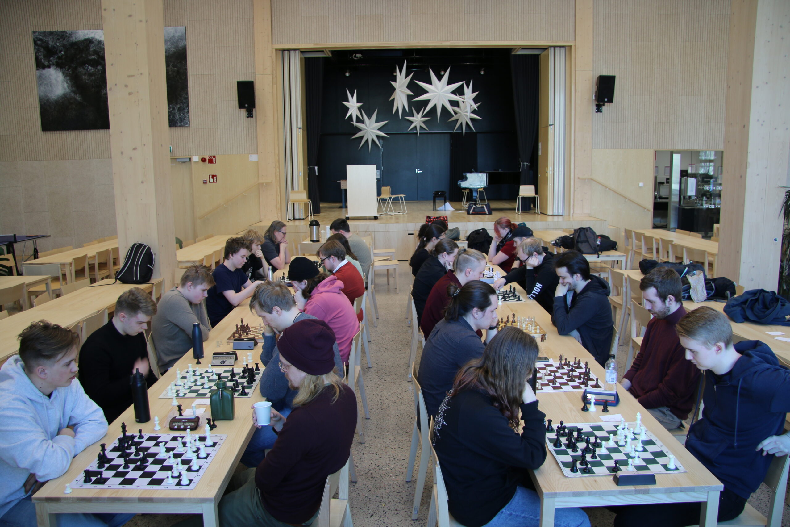 Monta nuorta pelaamassa shakkia koulun aulatilassa.